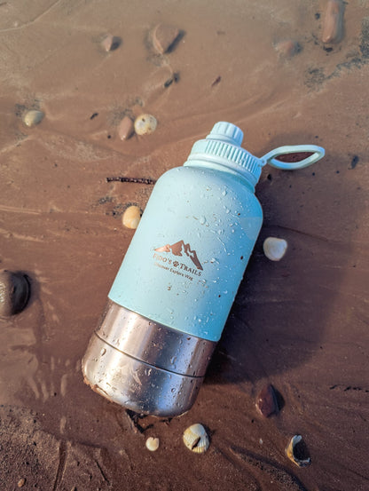 Coastal Blue 3-in-1 dog water bottle placed on sand during outdoor walk